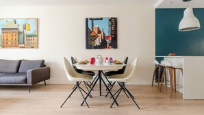 En moderne stue med spiseplads, der indeholder en sofa, et bord med stole og en køkkenø med barstole.