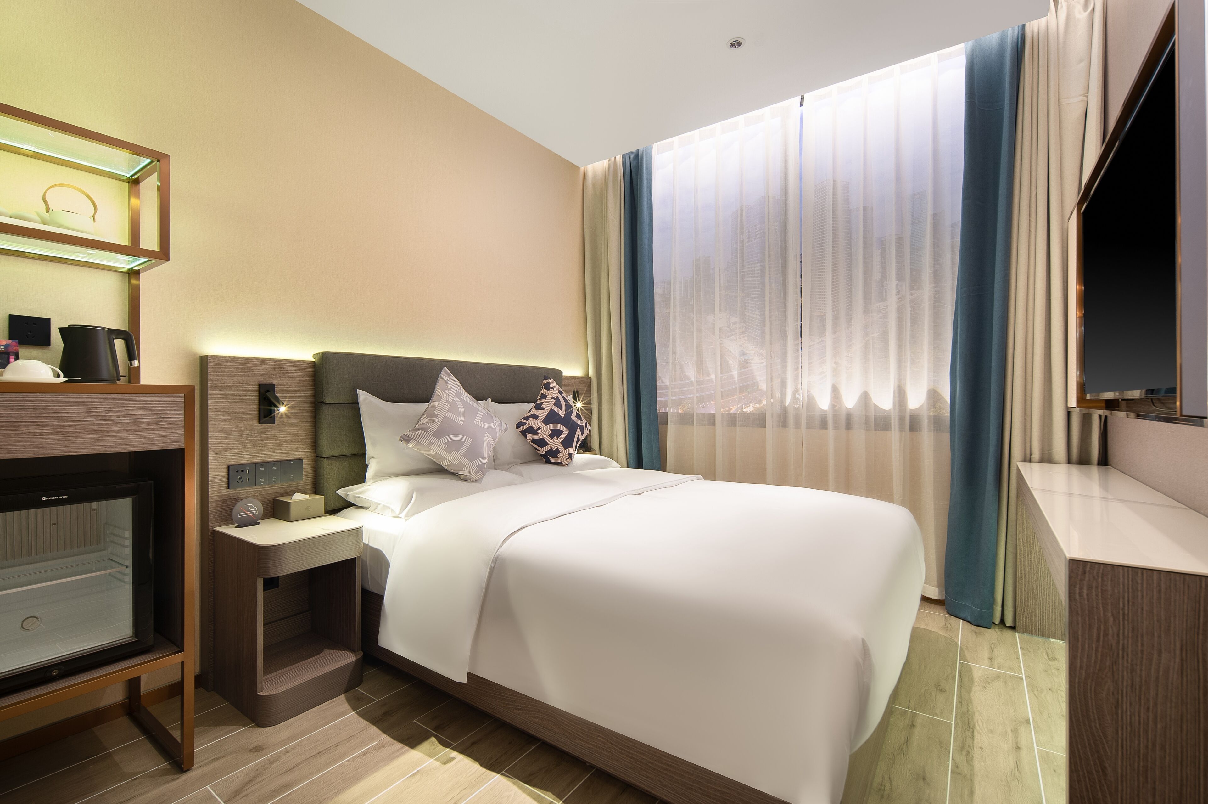 A hotel room with a bed, bedside table, lamp, and a television.