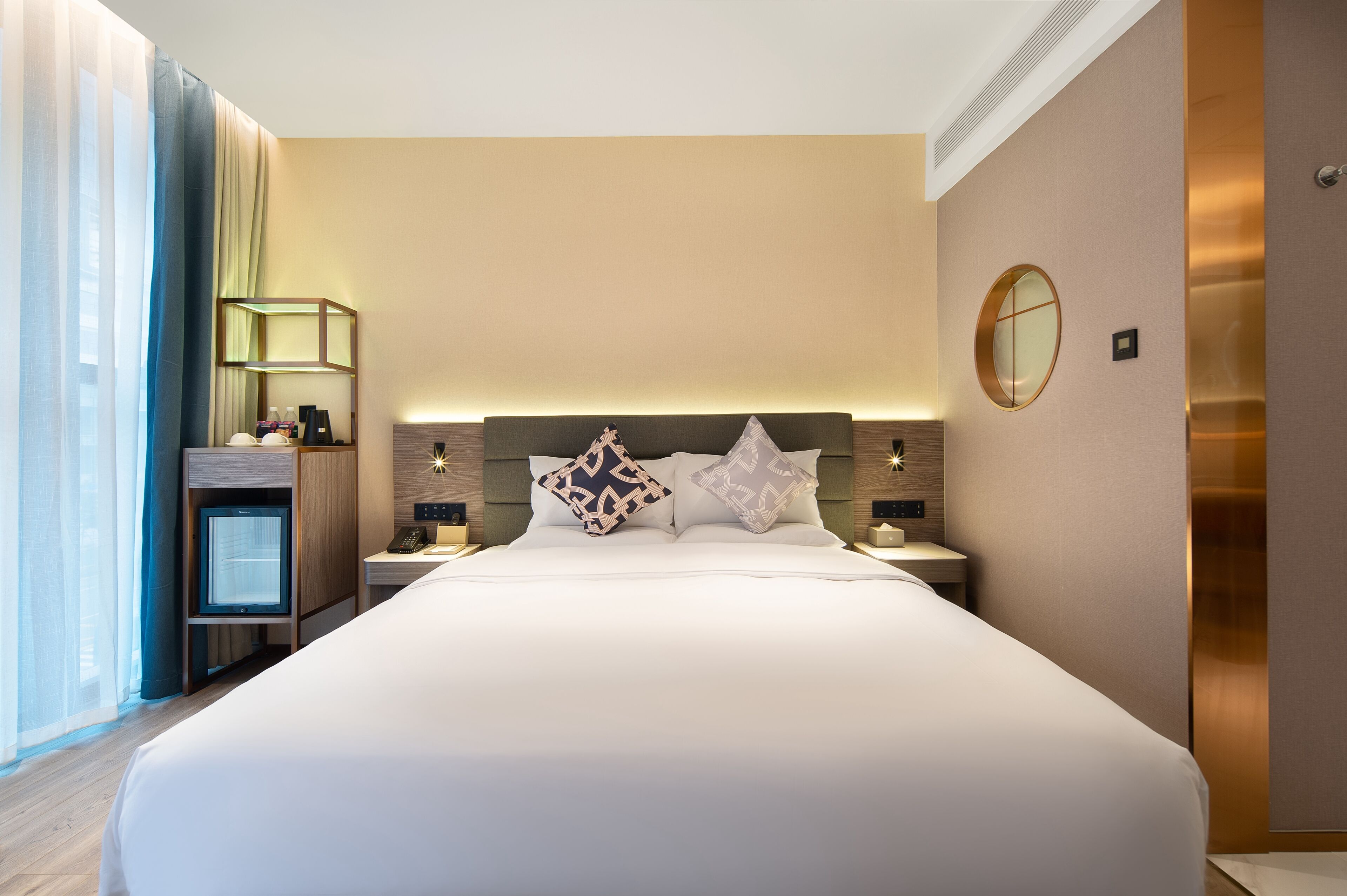 A modern hotel room with a large bed, bedside tables, a TV, and a mirror on the wall.