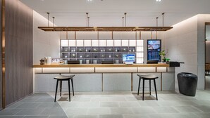 A modern reception area with a counter, two stools, a digital screen, and a plant. - Palace Hotel Shenzhen Luohukou (Shenzhen)