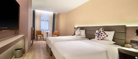 Een hotelkamer met twee bedden, een televisie, een tafeltje en een stoel.