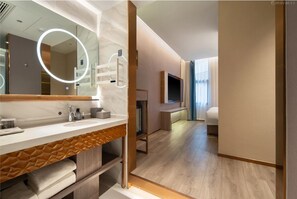 Ein modernes Badezimmer in einem Hotel, mit einem großen Spiegel, Waschtisch und Fernseher.
