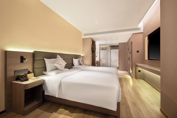 Una habitación de hotel moderna con una cama grande, mesitas de noche, televisión y zona de ducha.