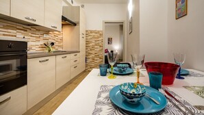 Eine moderne Küche mit hellen Holzschränken, einem eingebauten Backofen und einer gemusterten Spritzschutzwand.