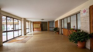 Ein geräumiger Korridor mit großen Fenstern, Holzvertäfelung und Topfpflanzen.