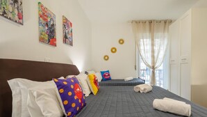 Ein Hotelzimmer mit einem großen Bett, zwei kleineren Betten und einem Fenster mit Vorhängen.