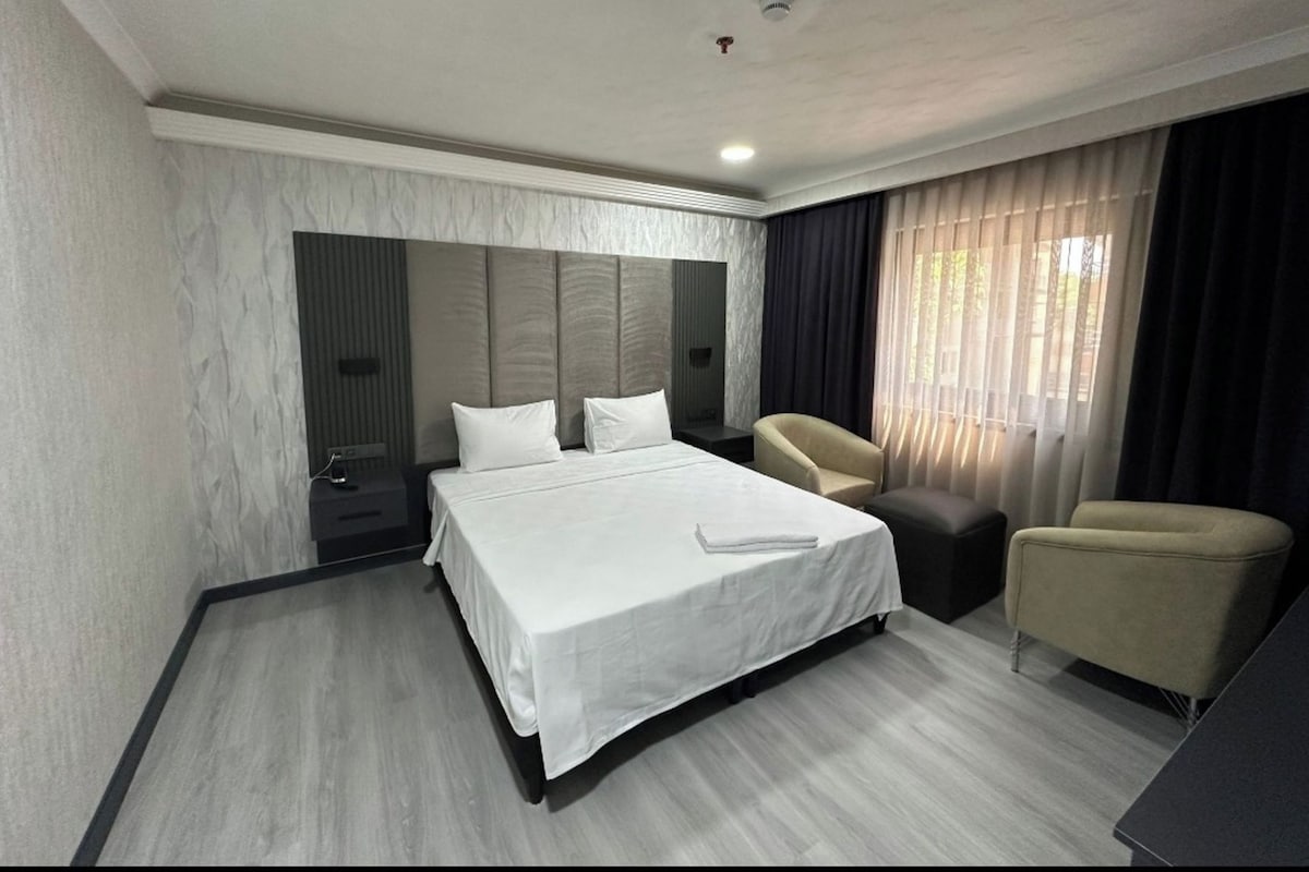 A modern hotel room with a large bed, a desk, and a chair.