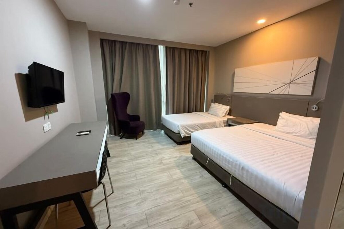 Una habitación de hotel con una cama, un escritorio, una silla y un televisor.