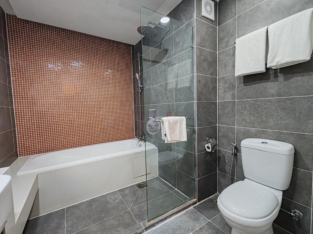 Un baño moderno con ducha de vidrio, bañera blanca y retrete.