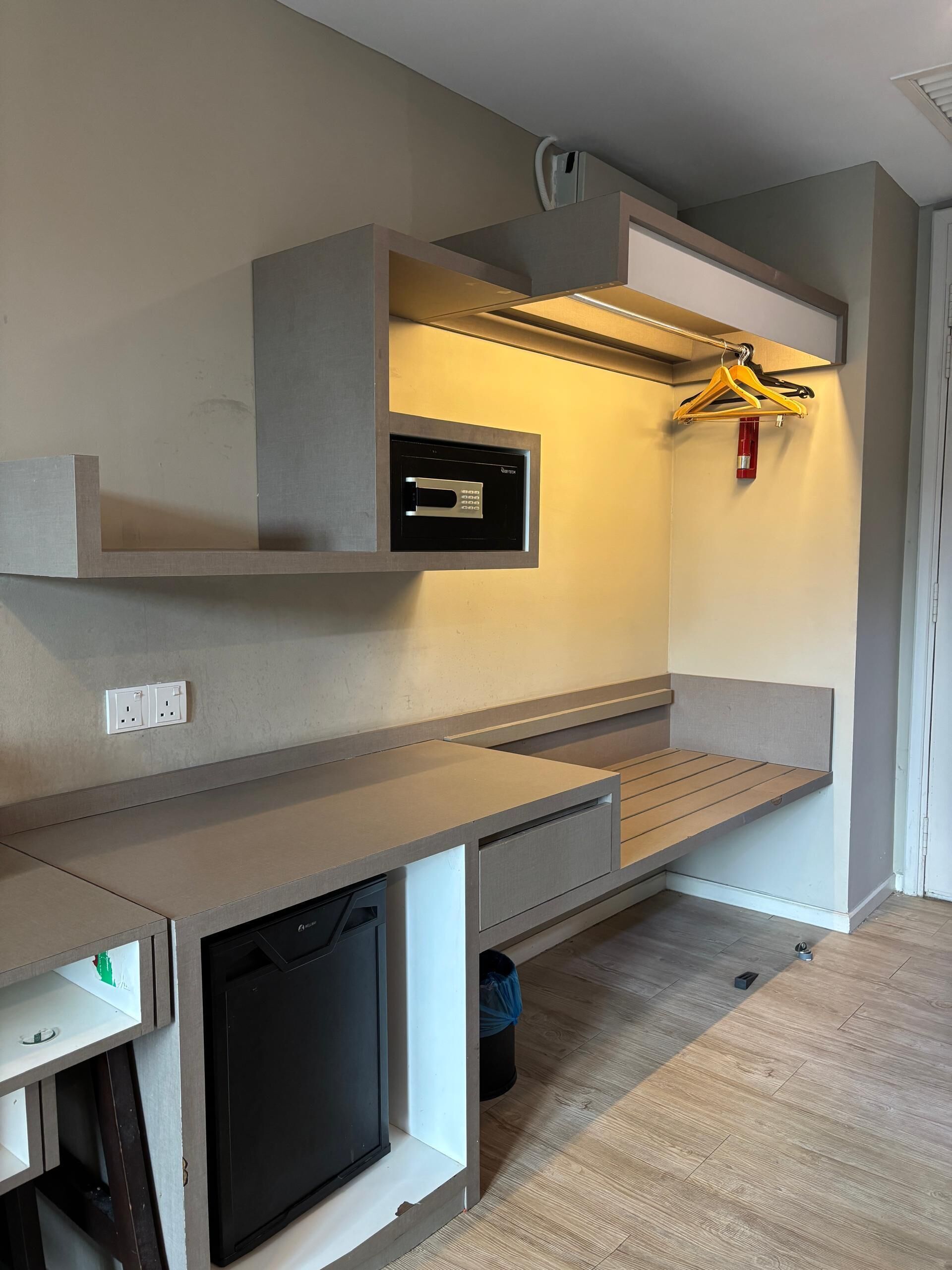 A modern, minimalist room with built-in storage, a built-in TV, and a coat rack.