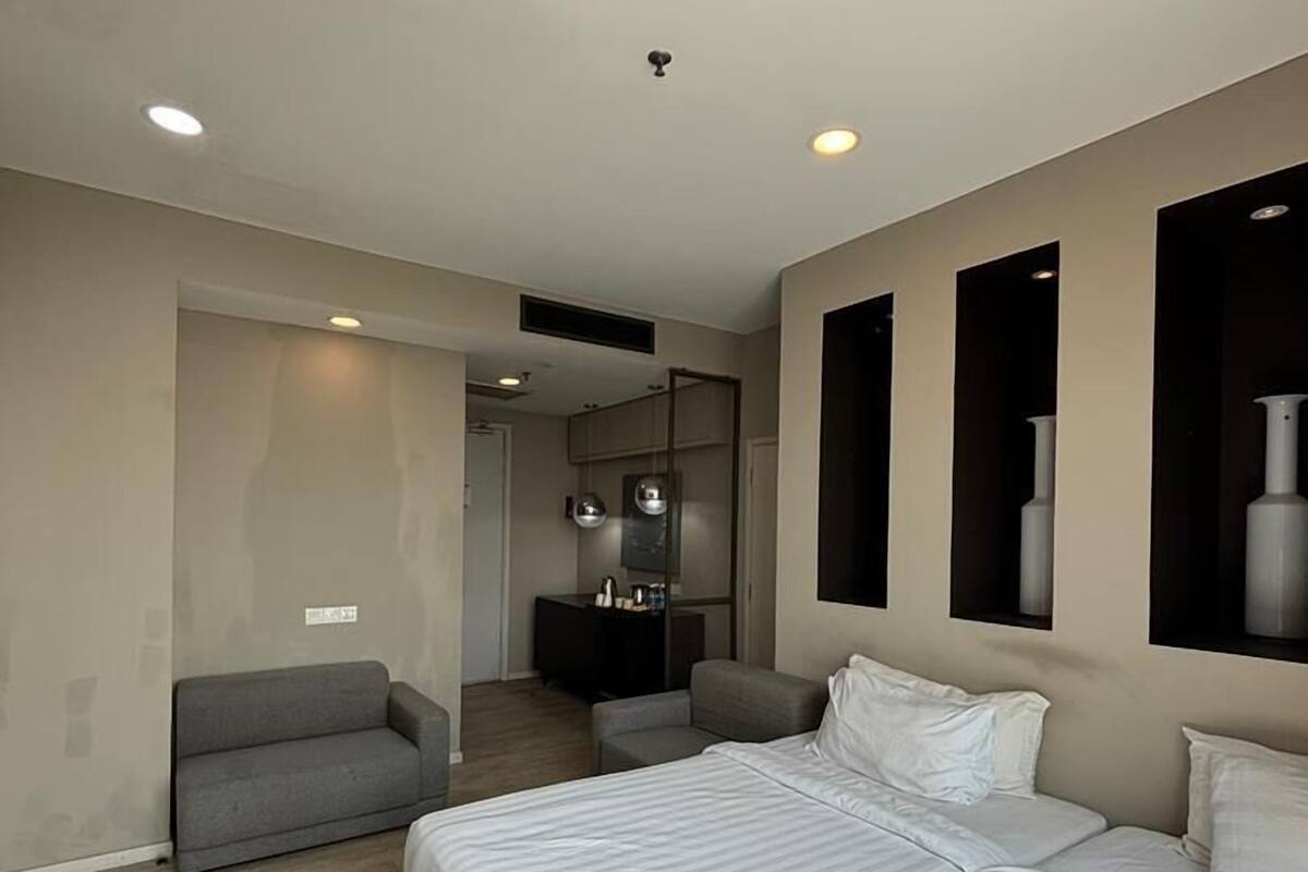 A modern hotel room with a large bed, a sofa, a desk, and a television.