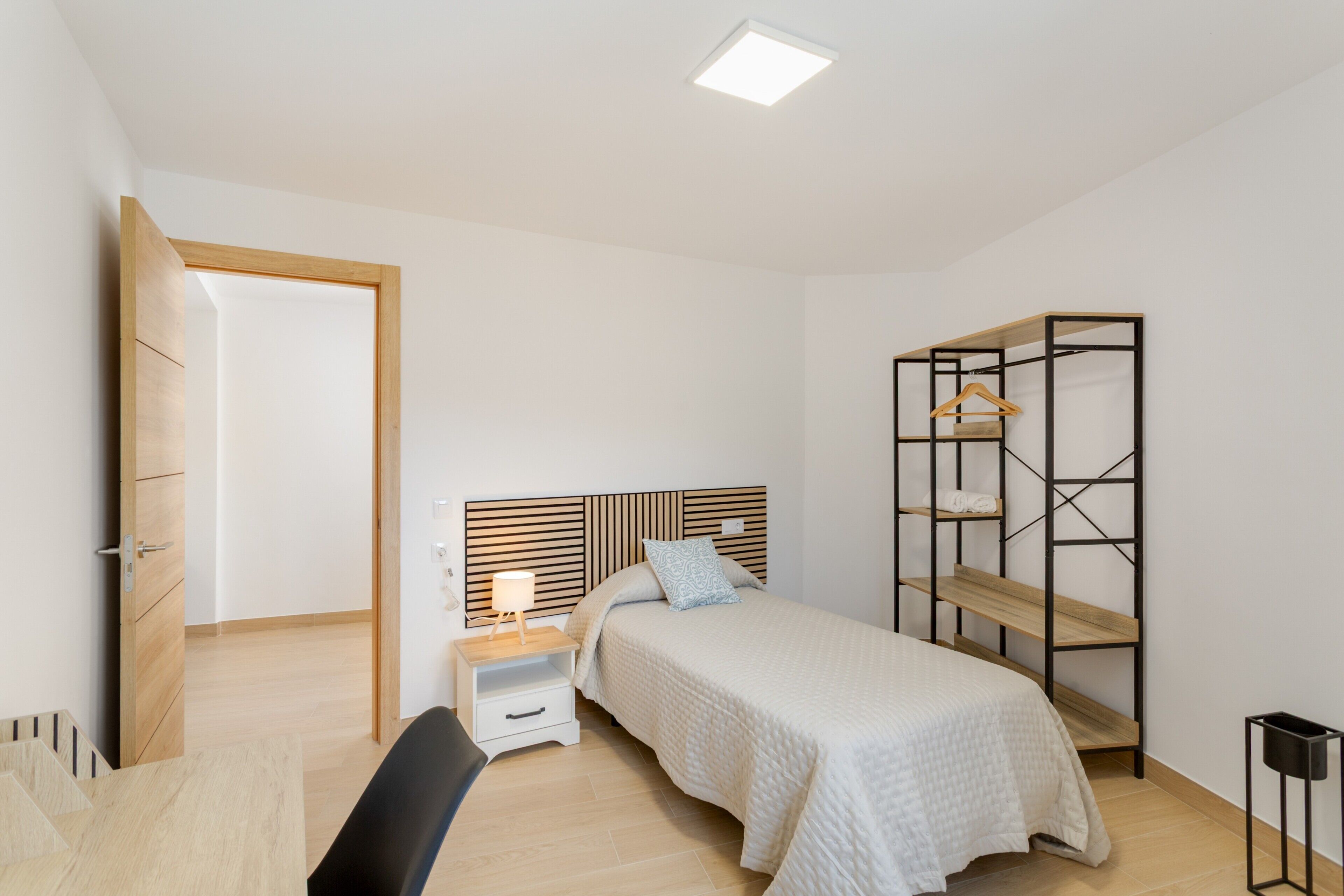 A bedroom with a bed, bedside table, and a built-in wardrobe.
