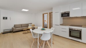 Una cucina moderna con mobili bianchi, forno integrato e zona pranzo con tavolo e sedie rotonde.