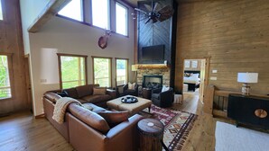 A spacious living room with a large leather sofa, a fireplace, and a ceiling fan. - Luxe Cabin, View, 4 Bedrooms, Hot Tub, 3 Kings, Private, 8 min to DT BR (Blue Ridge)