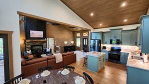 A modern kitchen with a central island, built-in appliances, and a dining area with a wooden table and chairs. - Luxe Cabin, View, 4 Bedrooms, Hot Tub, 3 Kings, Private, 8 min to DT BR (Blue Ridge)