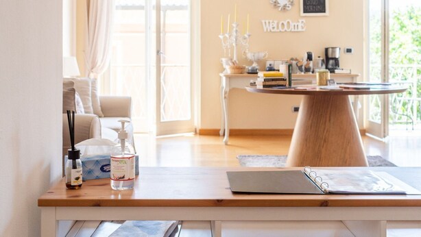 A well-lit room with a wooden table, a laptop, and a notebook. There is a "Welcome" sign on the wall and a window with curtains. - Charming abode with Arena view | 3 cam. 6 guests (Verona)