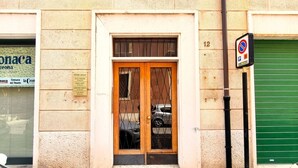 A building with a wooden door and barred windows, a green shuttered door, and a parking sign. - Charming abode with Arena view | 3 cam. 6 guests (Verona)