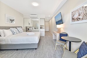 Een hotelkamer met een bed, een bureau, een stoel, een televisie en een spiegel.