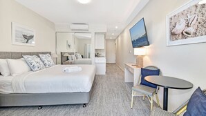 A hotel room with a bed, a desk, a chair, a TV, and artwork on the walls. - Pacific Blue Unit 175 Dual Swim Up B (Salamander Bay)