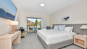 A hotel room with a bed, bedside table, desk, chair, and a view of the pool and mountains. - Pacific Blue Unit 175 Dual Swim Up B (Salamander Bay)