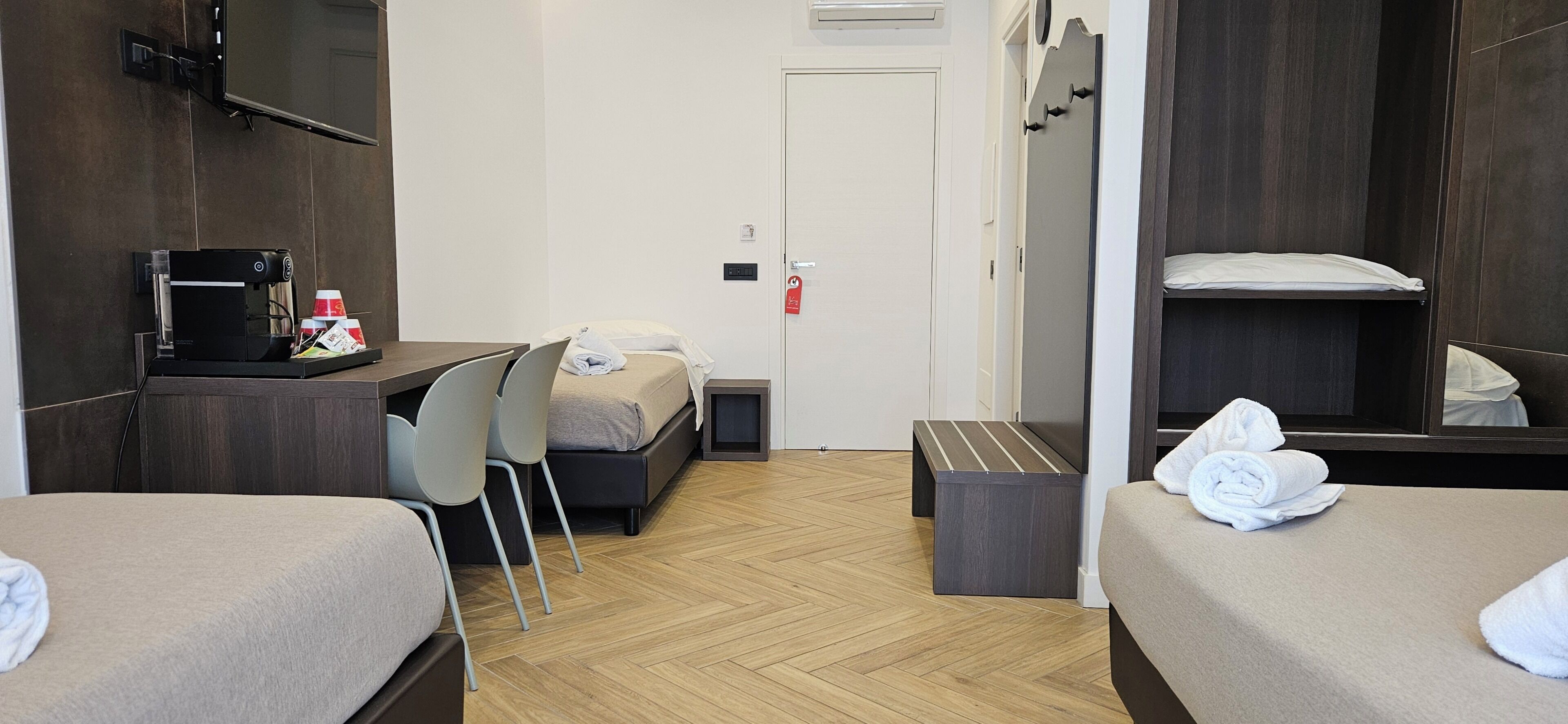 Une chambre d’hôtel avec deux lits, un bureau avec une machine à café, une télévision et un miroir.