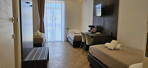 Hotelkamer met een bed, een bureau met een koffiezetapparaat, een stoel en een aan de muur bevestigde televisie.