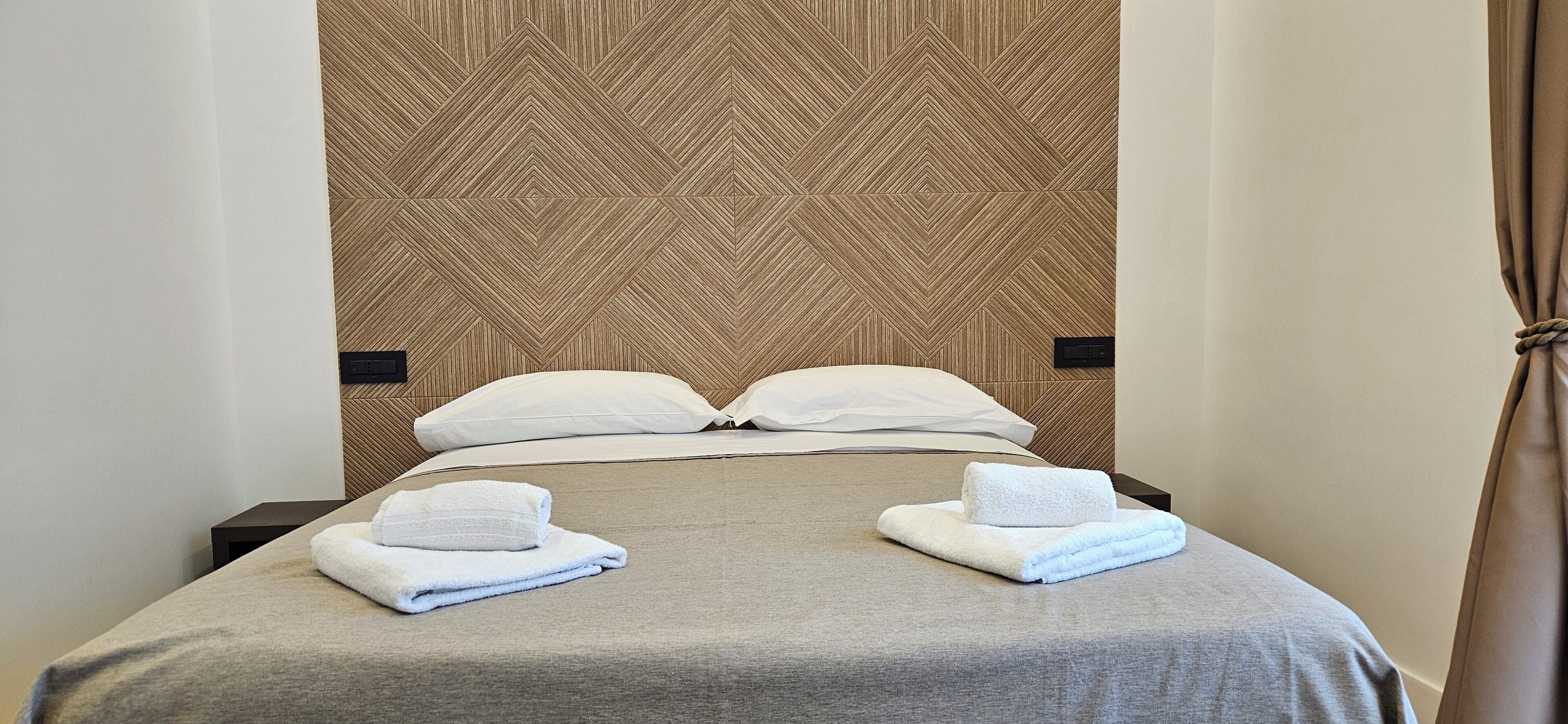 Una cama bien hecha con dos almohadas y dos toallas dobladas.