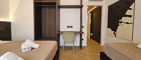 A hotel room with two beds, a desk, a chair, a map on the wall, and a wardrobe.