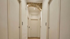 Un passadís amb un paviment de motius de serra i parets blanques, i una arcada de pedra al final.