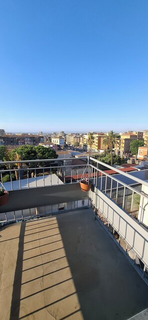 A rooftop terrace with a view of the cityscape, including buildings and palm trees. - Damablu  (Catania)