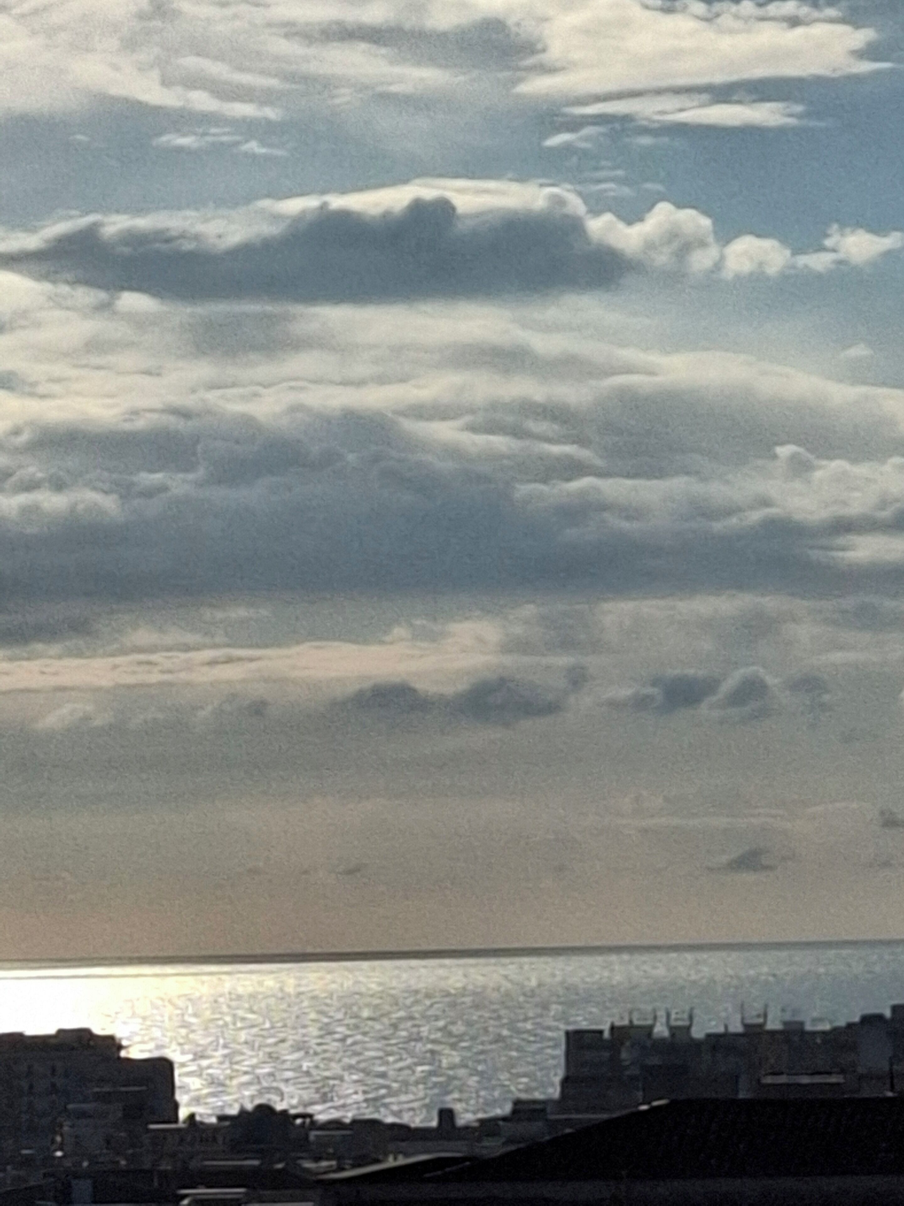 Paesaggio costiero con edifici e una distesa d'acqua sotto un cielo nuvoloso.