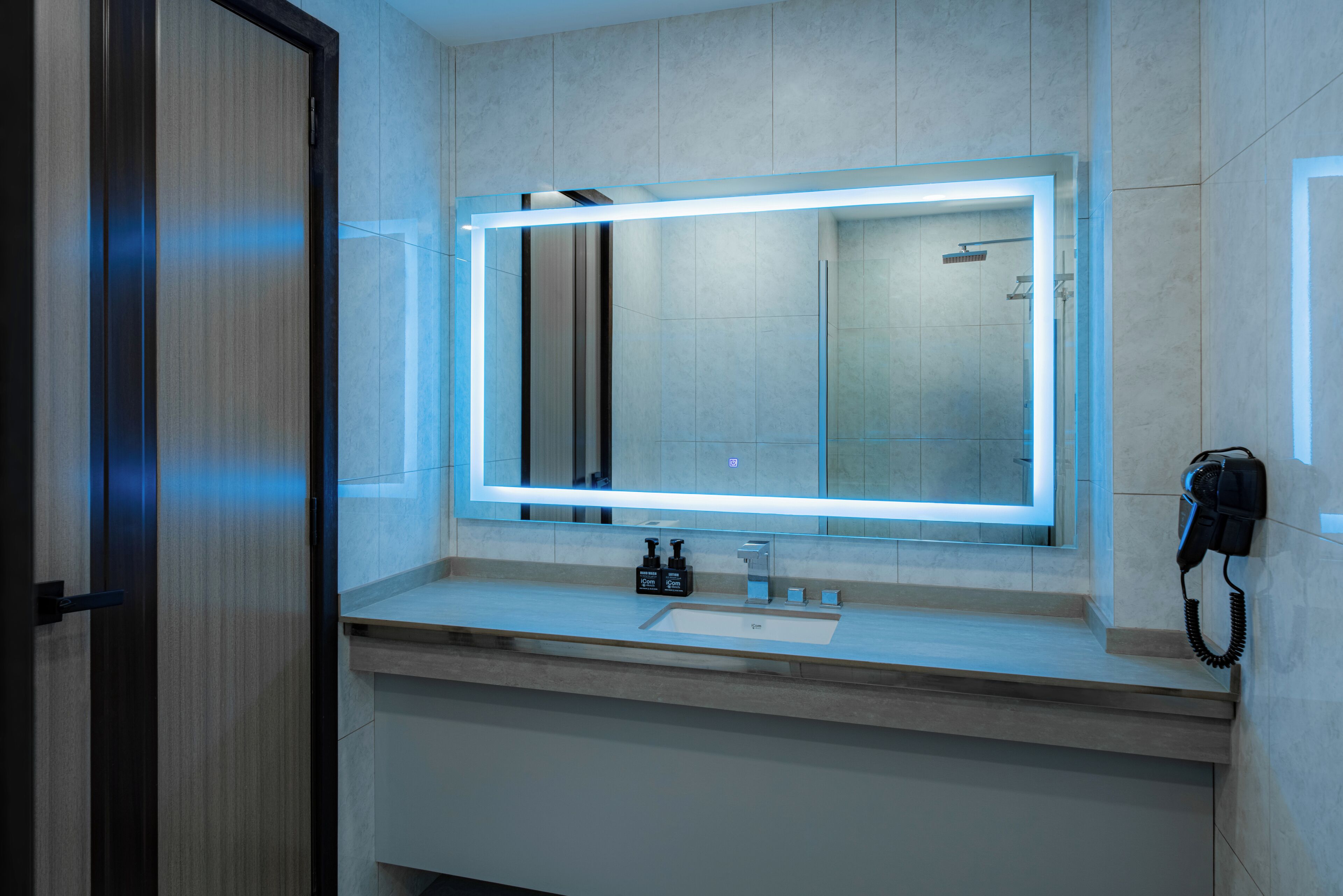 A modern bathroom with a large mirror, a sink, and a telephone.