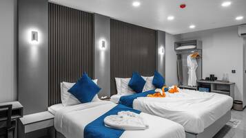 A modern hotel room with two beds, a desk, a chair, and a wardrobe.