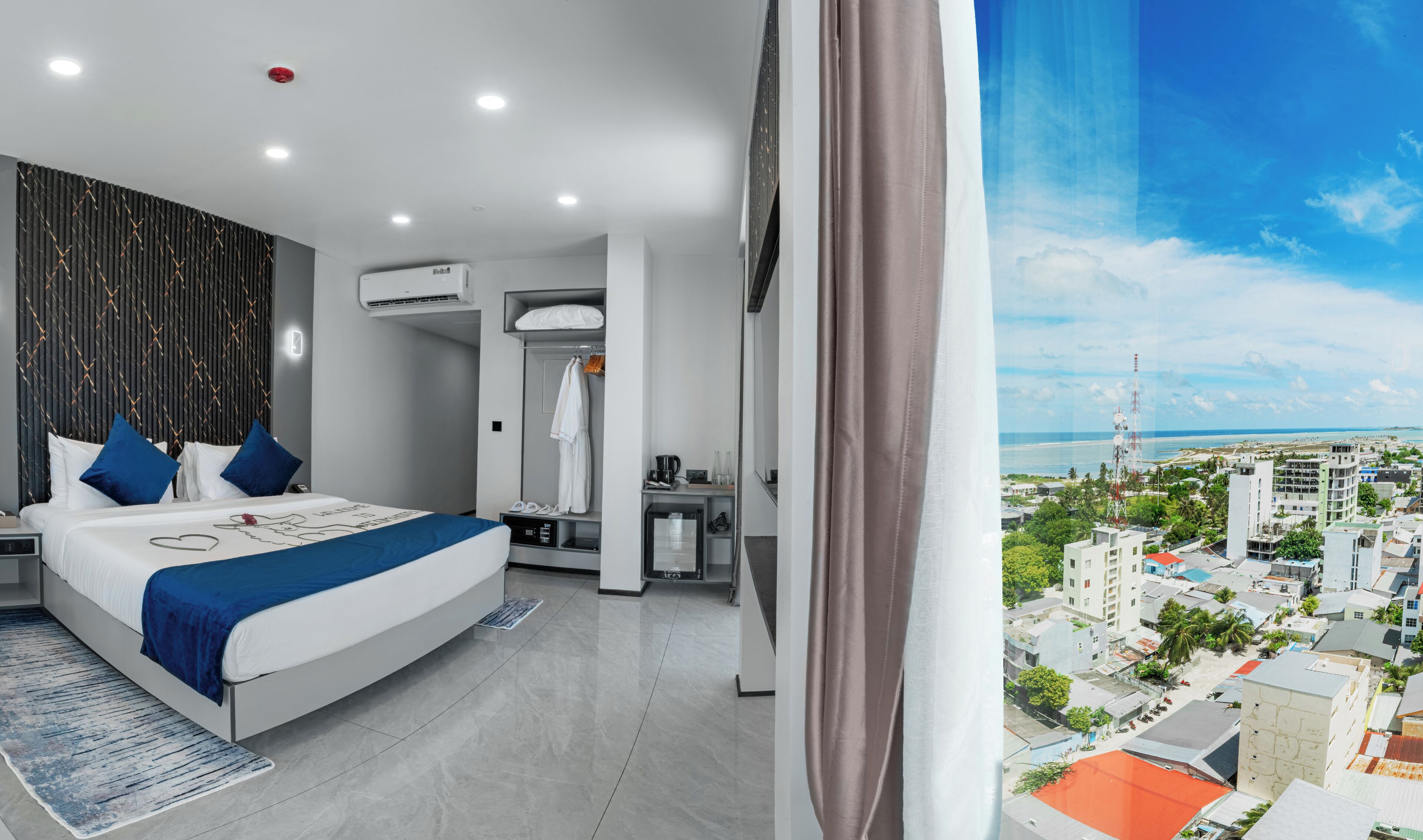 Una habitación de hotel moderna con una cama, un escritorio, un armario y vistas a la ciudad.