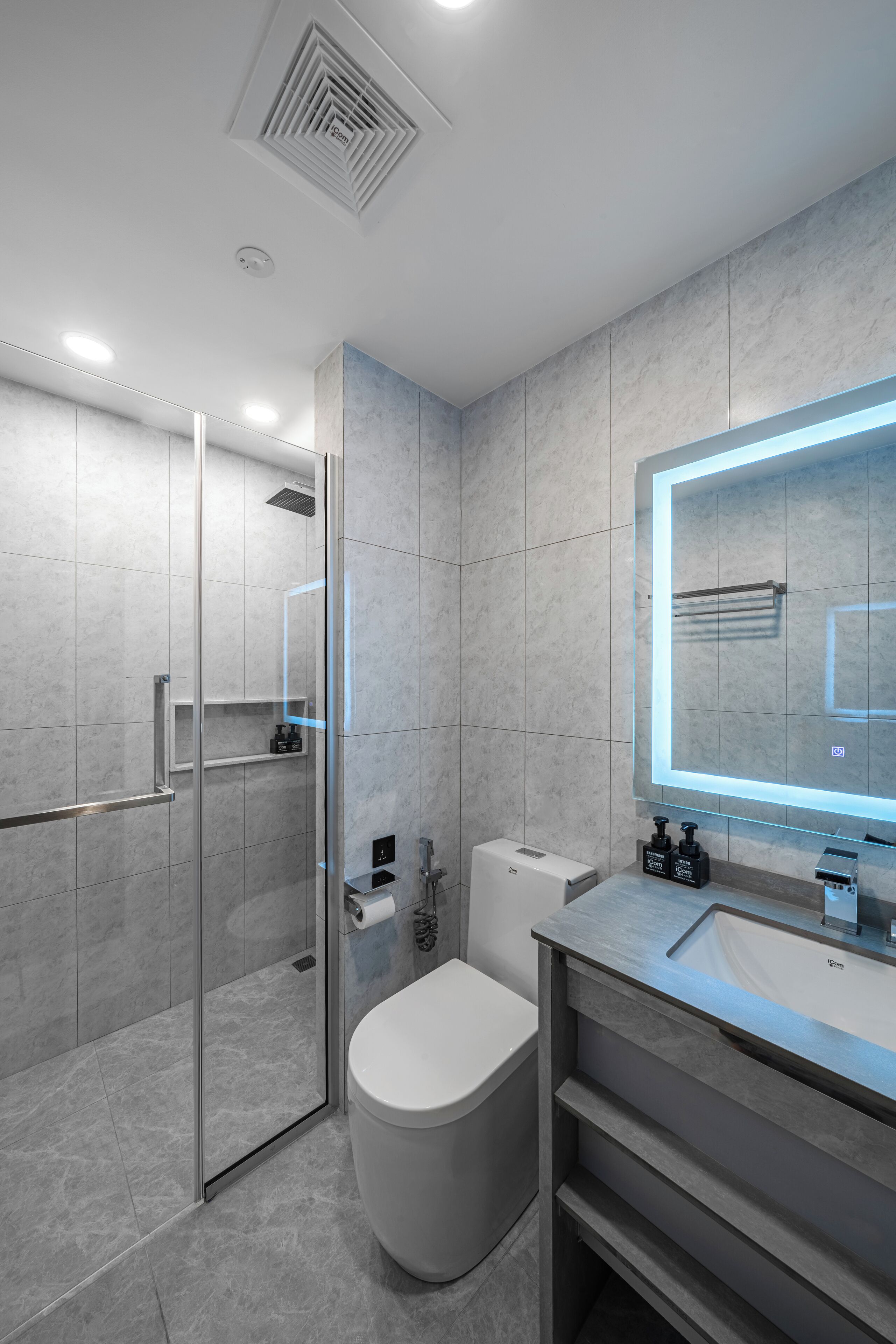A modern bathroom with a glass-enclosed shower, a toilet, and a vanity with a mirror.