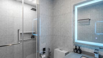 A modern bathroom with a glass-enclosed shower, a toilet, and a vanity with a mirror.