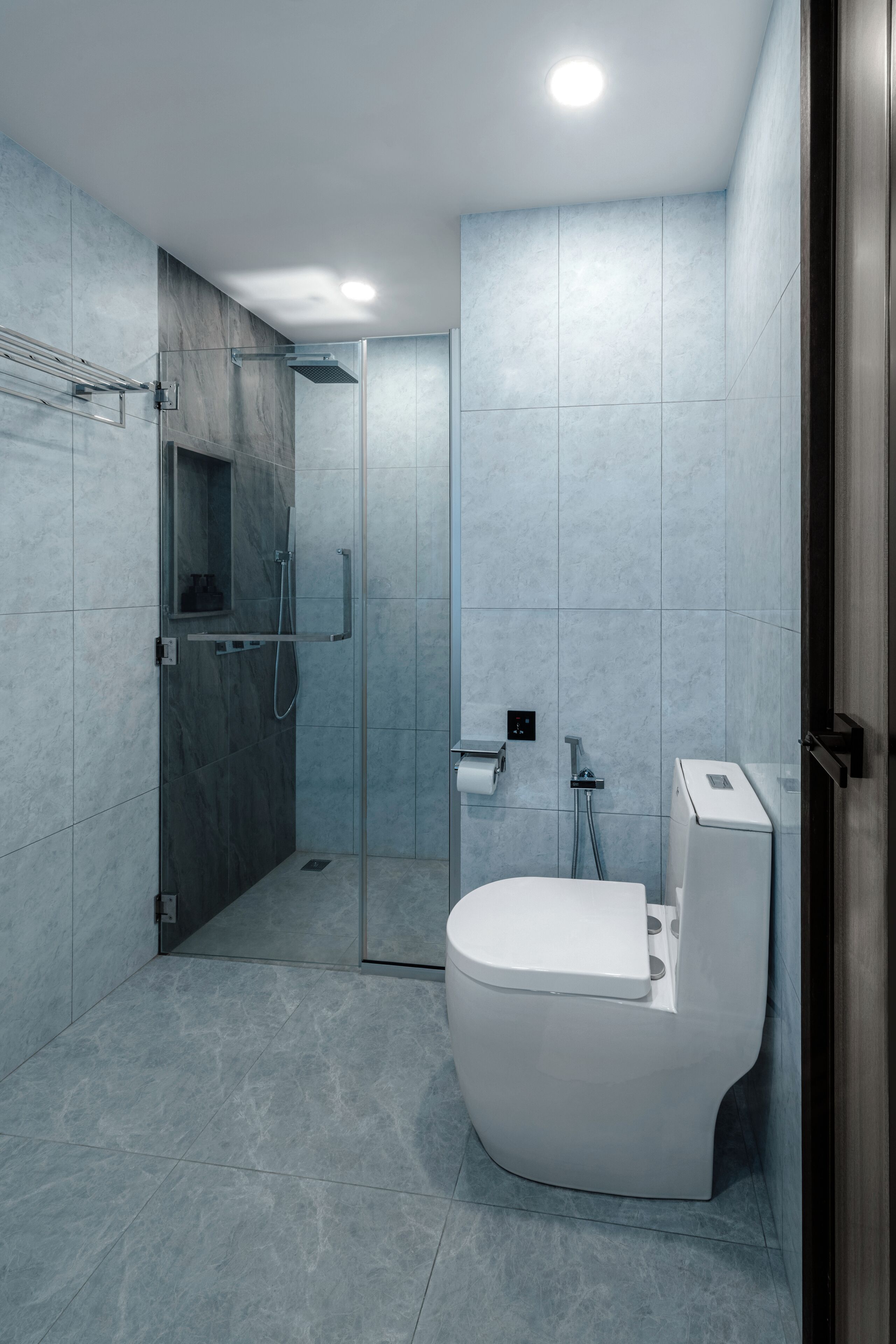 Un baño moderno con cabina de ducha de vidrio, inodoro y lavamanos.