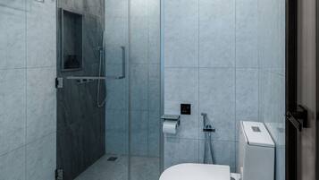 Un baño moderno con cabina de ducha de vidrio, inodoro y lavamanos.