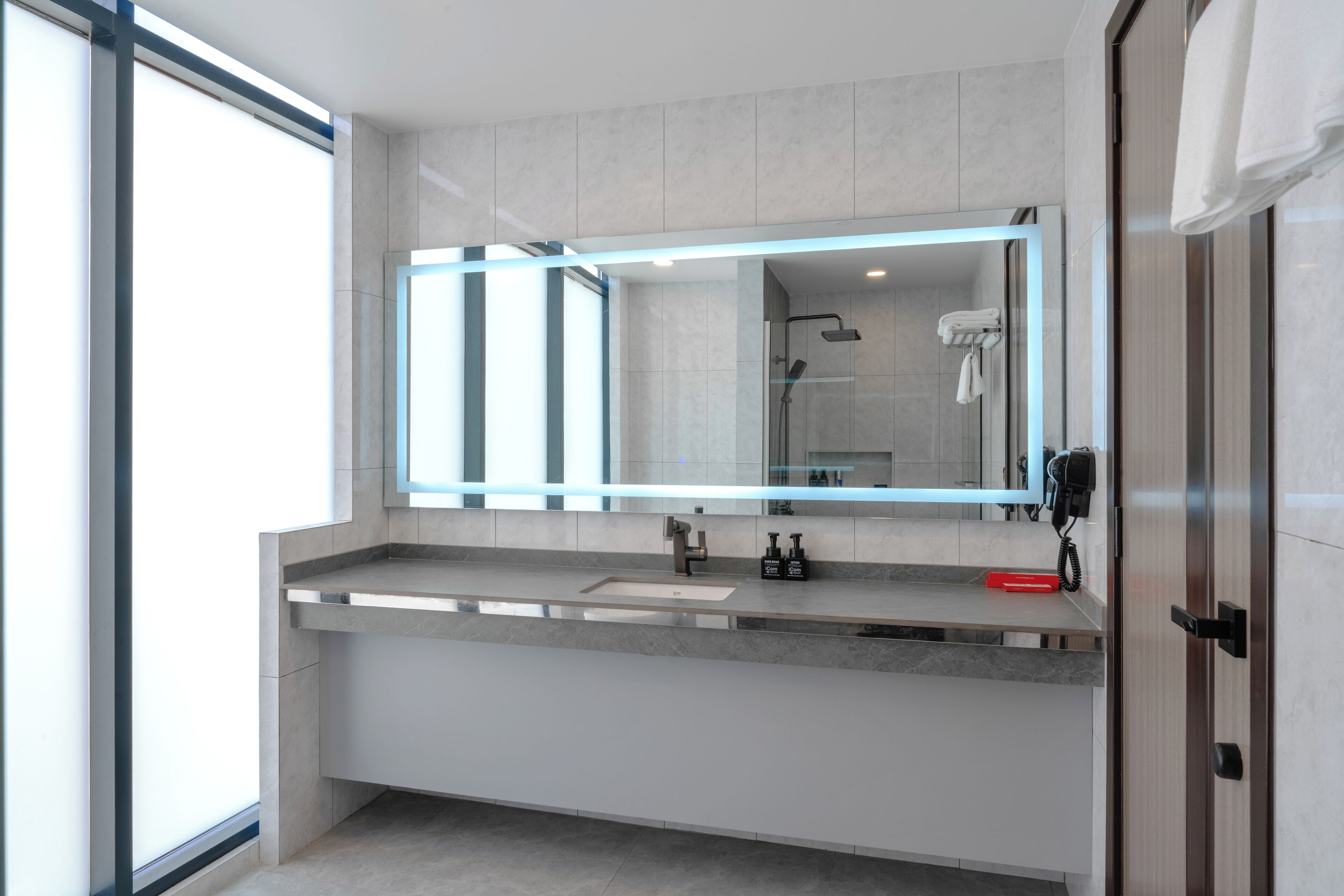 Un baño moderno con un espejo grande, un lavamanos y una zona de ducha.