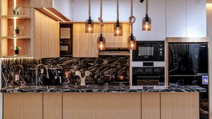 A modern kitchen with a marble countertop, wooden cabinets, and a built-in oven.