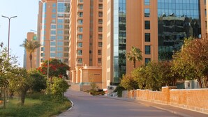 A modern hotel with multiple high-rise buildings, featuring a prominent glass facade and a well-maintained surrounding area with greenery and a paved walkway.