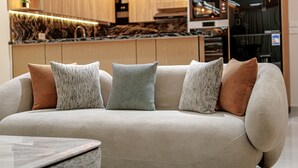 A modern living room with a beige sofa, multiple cushions, and a marble coffee table.