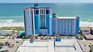 Un grand hôtel à plusieurs étages, avec vue sur la plage et un parking.