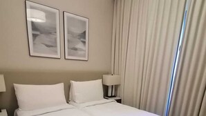 A hotel room with a large bed, two bedside tables, a lamp, and two framed pictures on the wall.