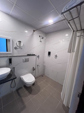 A modern bathroom with a sink, toilet, and shower. - Decan County (Bengaluru)