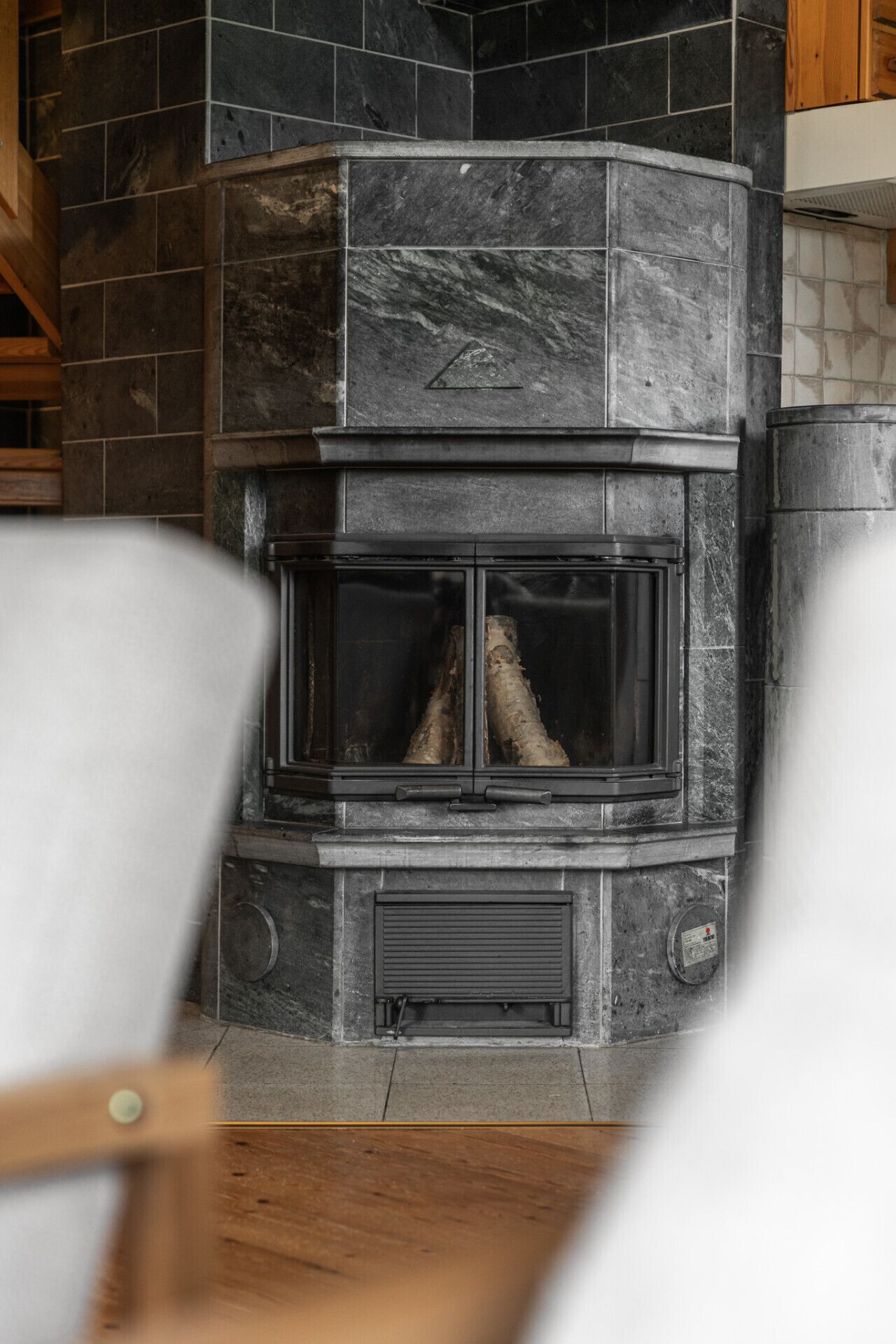 Ein Kamin aus Stein mit Glastür, eine eingebaute Bank und ein Holzkabinett darüber.
