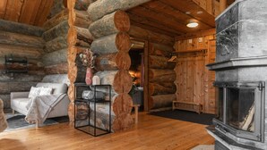 A log cabin interior with a fireplace, wooden furniture, and a cozy ambiance. - Villa Rukatörmä - Comfy Cabin Retreat in Ruka (Kuusamo)