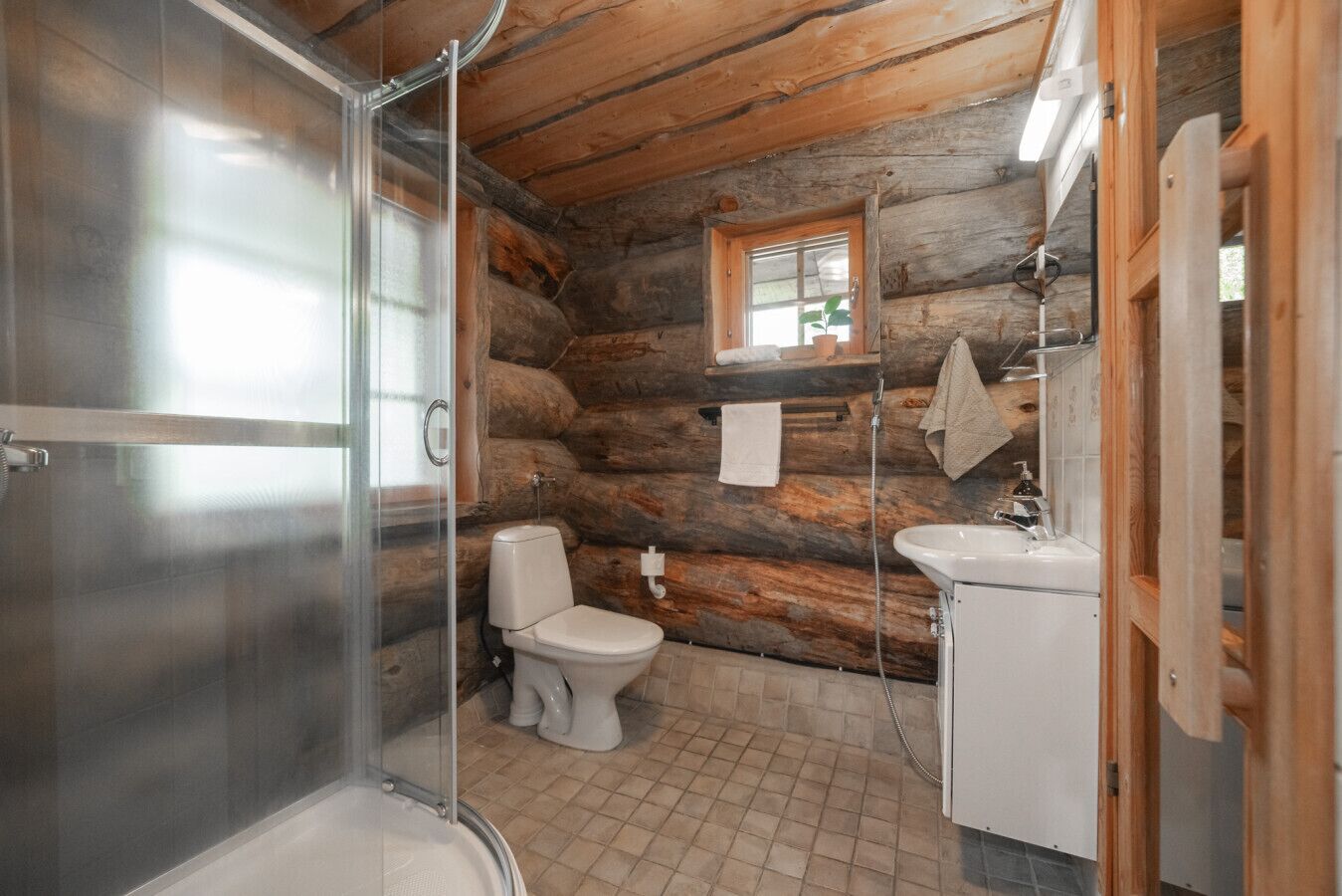 A bathroom with a glass shower enclosure, a toilet, and a sink.