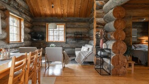A log cabin interior with a dining area, a sofa, and a fireplace. - Villa Rukatörmä - Comfy Cabin Retreat in Ruka (Kuusamo)
