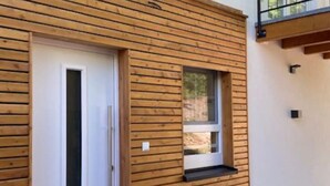 A modern building with horizontal wooden siding, a white door, and a small window with a black ledge.